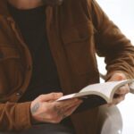 A man with tattoos reading a book.