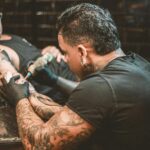 A tattoo artist using a tattoo gun.