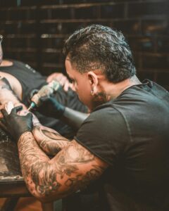 A tattoo artist using a tattoo gun.