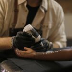 A tattoo artist applying lotion.